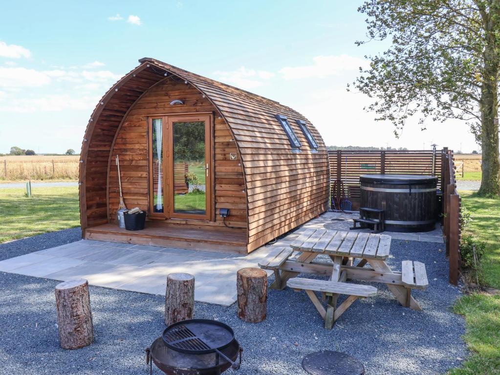a wooden cabin with a grill and a picnic table at Bouquet in Harpham