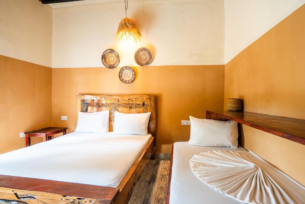 two beds in a room with clocks on the wall at La Fontana Zanzibar in Kendwa