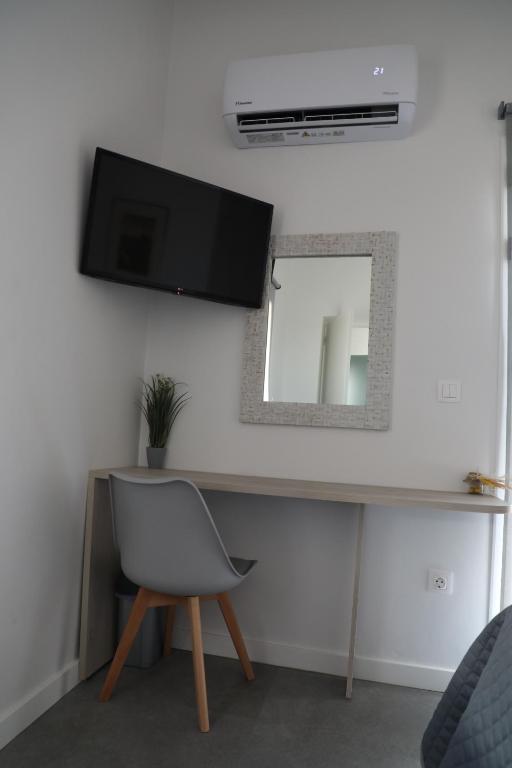 a room with a chair and a television on a wall at Serendipity Living in Kythira