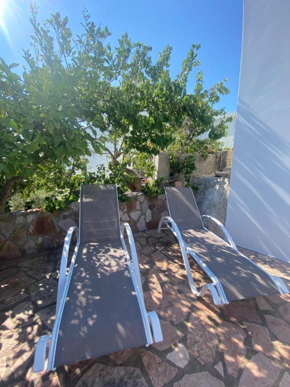 two metal chairs sitting on a patio near a tree at Serendipity Living in Kythira