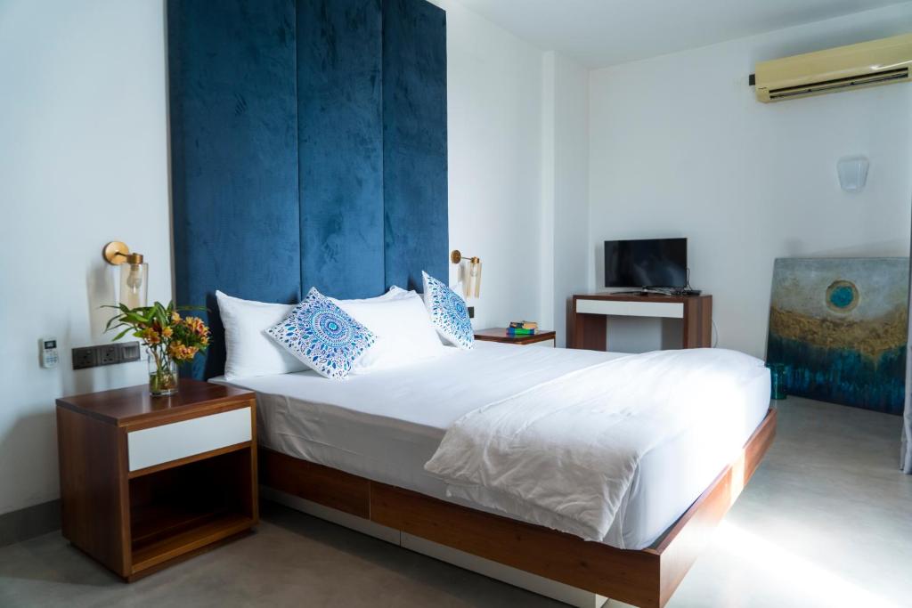 a bedroom with a bed with a blue accent wall at Four Petals Inn in Colombo