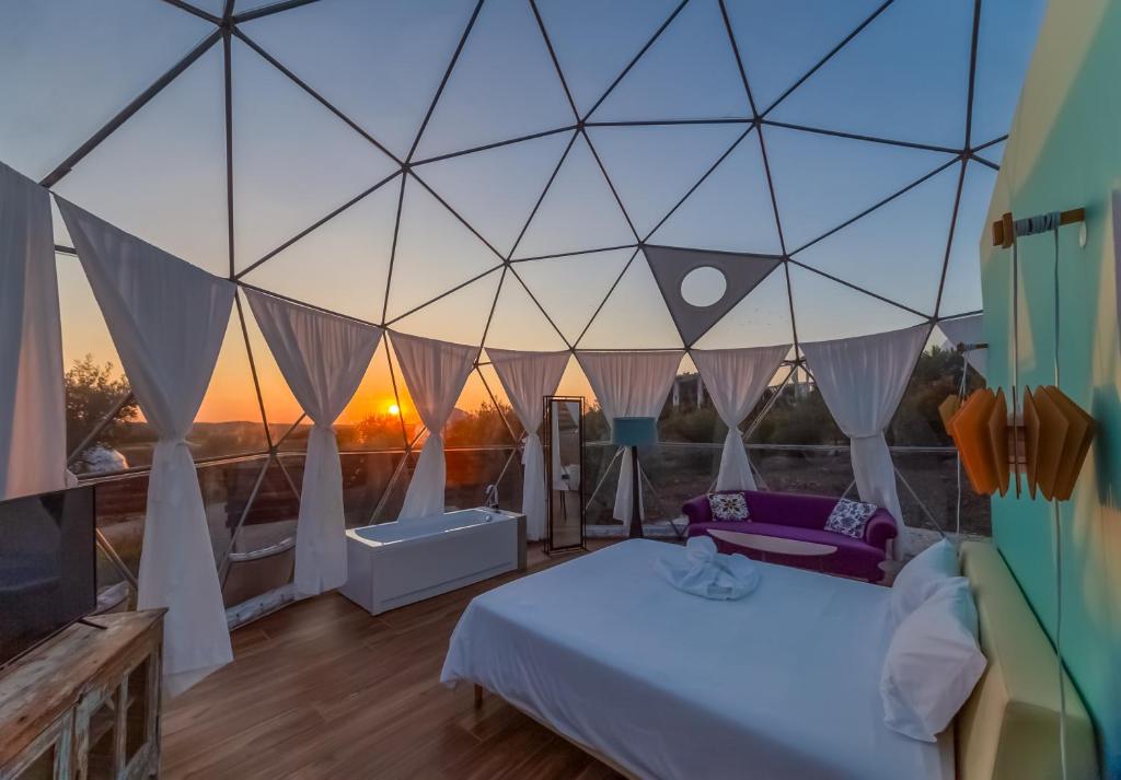 エストレモスにあるGlamping Skies - Adults Onlyのベッド1台、大きなガラスの壁が備わる客室です。