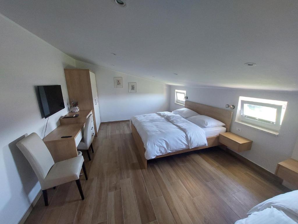 - une chambre avec un lit, un bureau et une télévision dans l'établissement Gostilna in pizzeria Pri Brajdi, à Komen