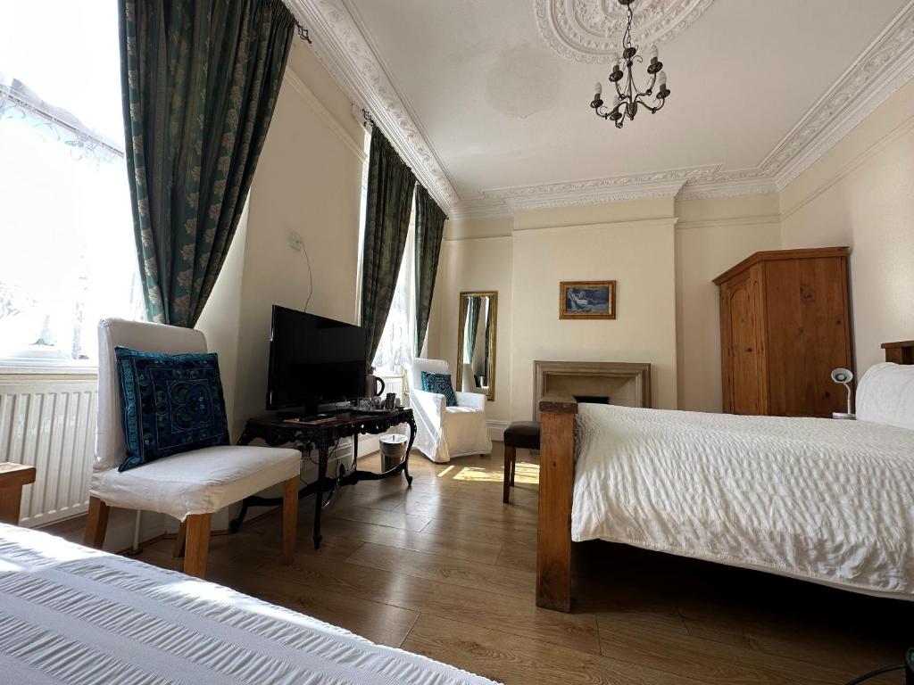 a bedroom with a bed and a desk and a tv at Manor Lodge Guesthouse in Keynsham