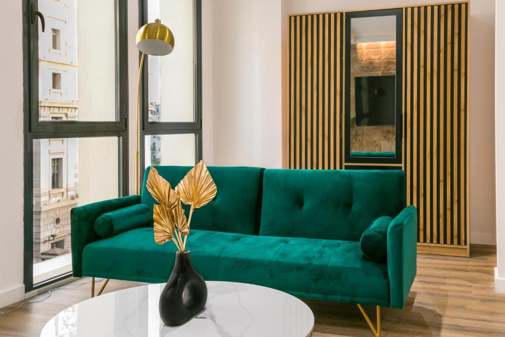 un sofá verde en una sala de estar con mesa en BOUTIQUE REYES CATÓLICOS, en Granada