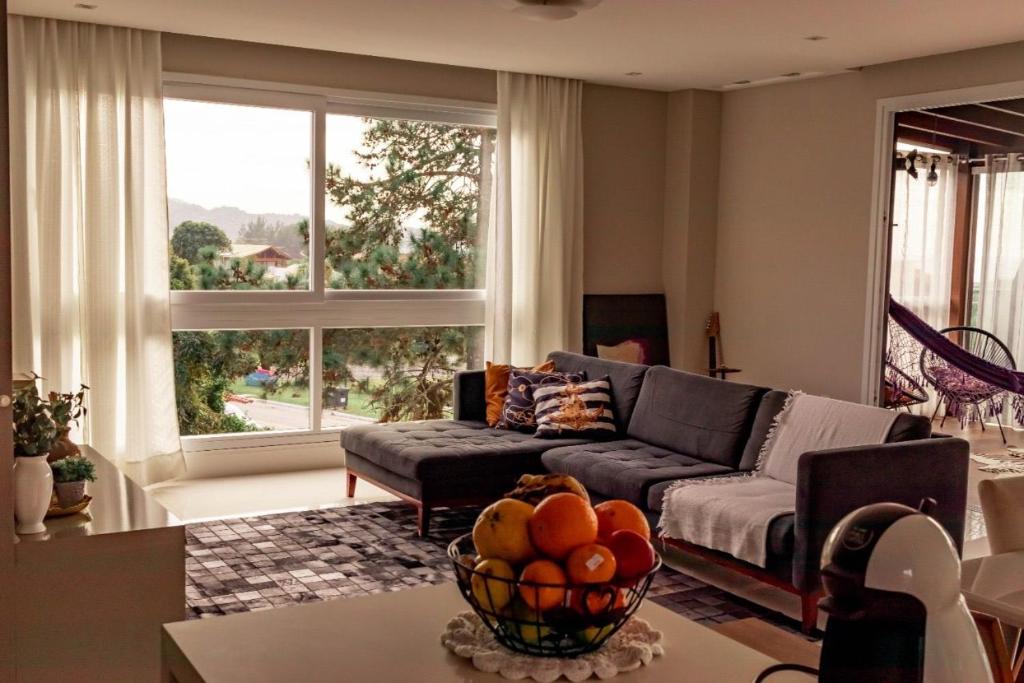 uma sala de estar com um sofá e uma tigela de fruta numa mesa em Morada do Estaleiro em Balneário Camboriú