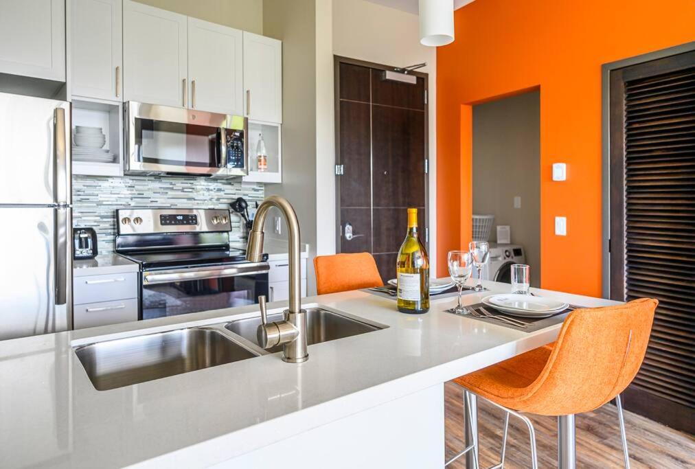une cuisine avec un évier et une cuisine aux murs orange dans l'établissement Private Downtown Apartment With Garage Parking, à Raleigh