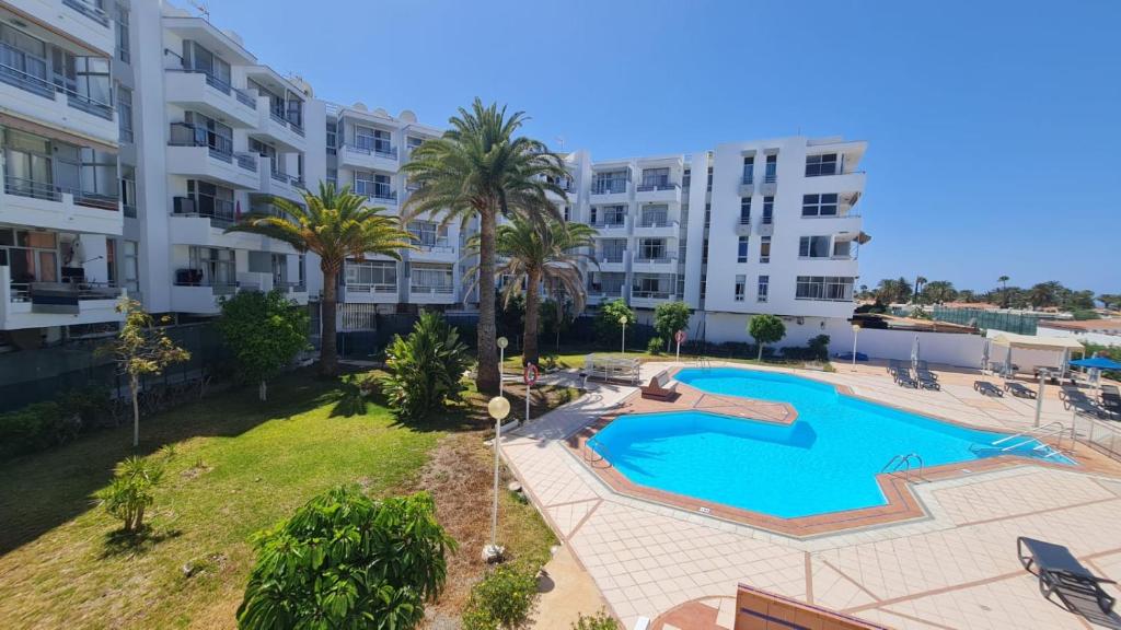 an apartment with a swimming pool and a building at Loris Home playa ingles 50mt from Yumbo by luca properties gran canaria in San Bartolomé de Tirajana