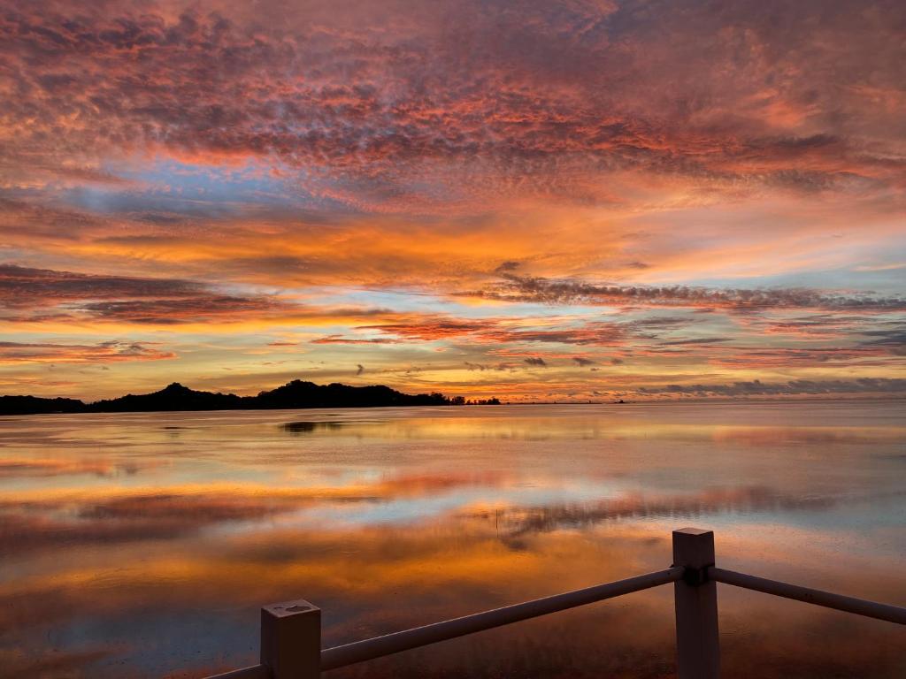 a sunset over a body of water with a fence at Seaward 270 degrees deluxe ocean view room with queen bed in Koror