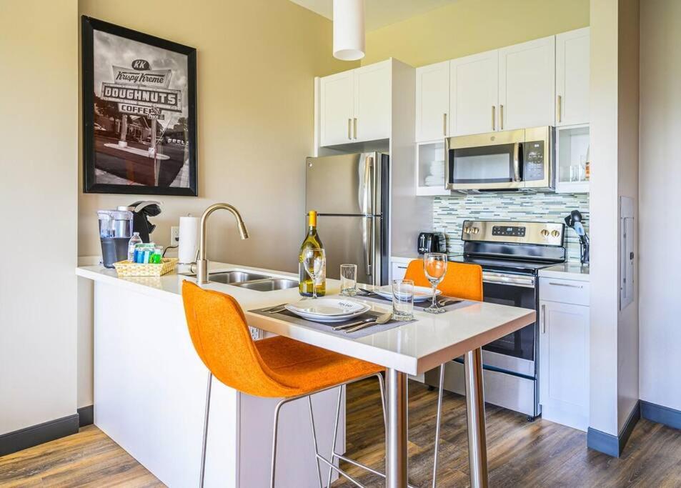 uma cozinha com uma mesa com cadeiras e electrodomésticos cor de laranja em Private Downtown Apartment With King Bed em Raleigh