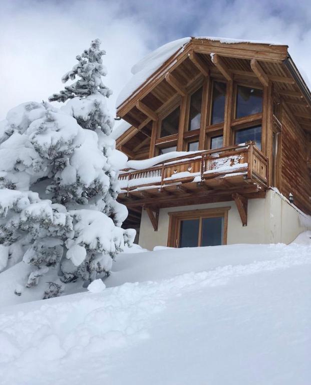 une cabane en rondins dans la neige avec un arbre enneigé dans l'établissement Chalet Loan, à Montgenèvre