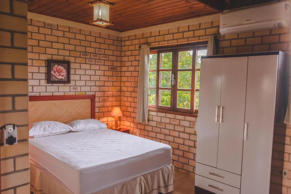 a bedroom with a bed in a brick wall at Hospedaria Nativa in Praia do Rosa