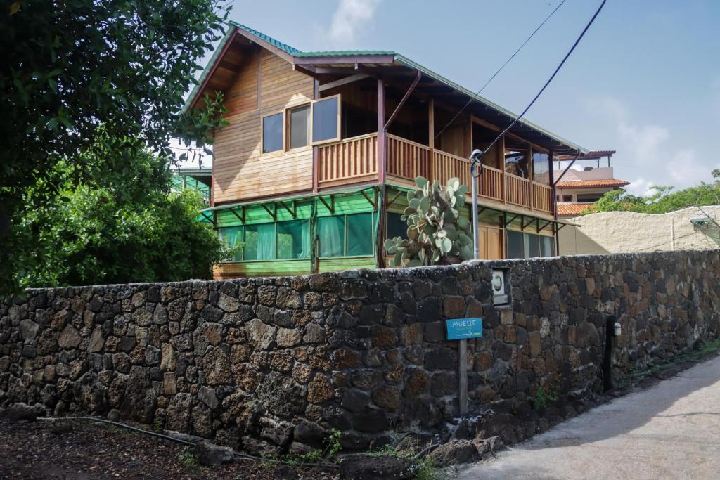 a wooden house behind a stone wall at Galapagos Chalet-Buda Chalet in Puerto Ayora