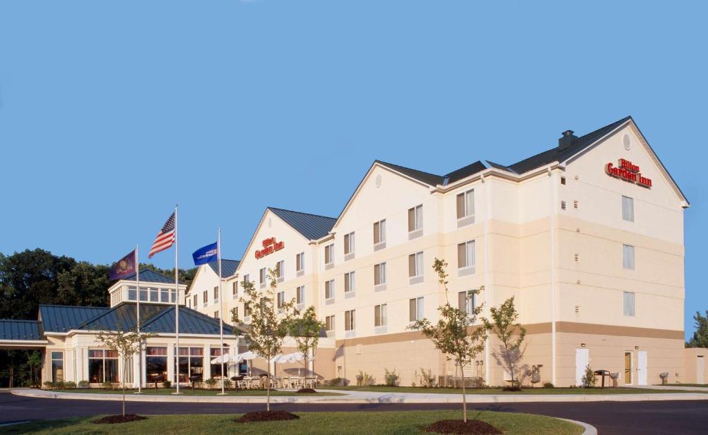 ein großes weißes Gebäude mit amerikanischer Flagge in der Unterkunft Hilton Garden Inn Gettysburg in Gettysburg