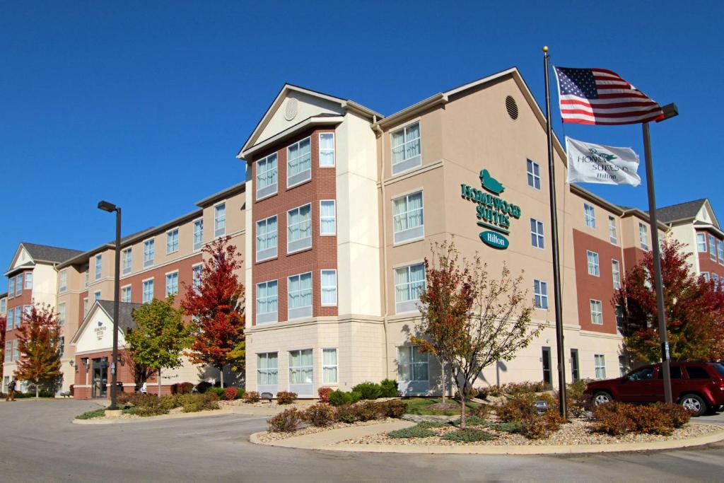 an exterior view of a hotel with an american flag at Homewood Suites by Hilton Bloomington in Bloomington