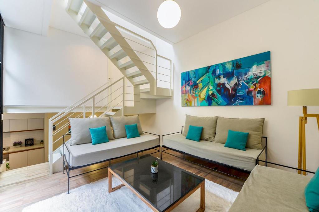 una sala de estar con 2 sofás y una escalera en Fliphaus Honduras 5750 - Lux 3 Bd Palermo H en Buenos Aires
