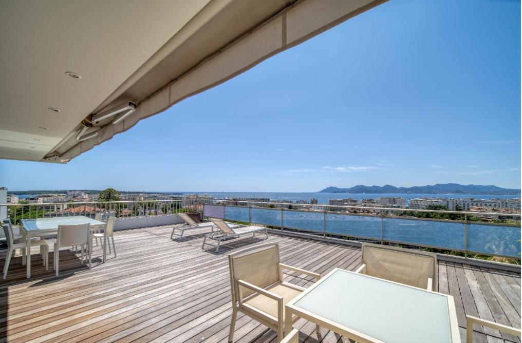 a balcony with tables and chairs on top of a building at Penthouse Cannes 100m2 avec 2 suites et terrasse 80m2 in Cannes