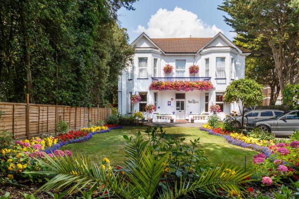 a white house with flowers in the yard at Balincourt in Bournemouth