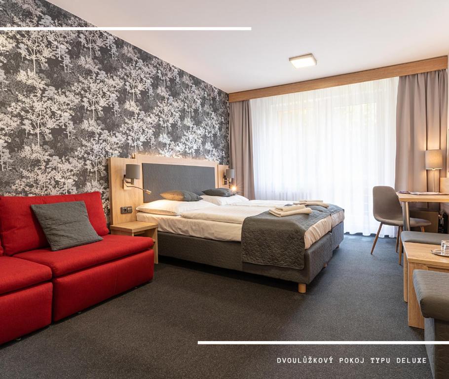 une chambre d'hôtel avec un lit et un canapé rouge dans l'établissement Hotel Kamzík ***, à Malá Morávka