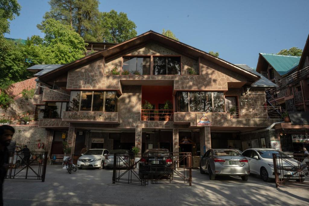 a building with cars parked in front of it at Maisonette Firhill Hotel & Resort in Murree