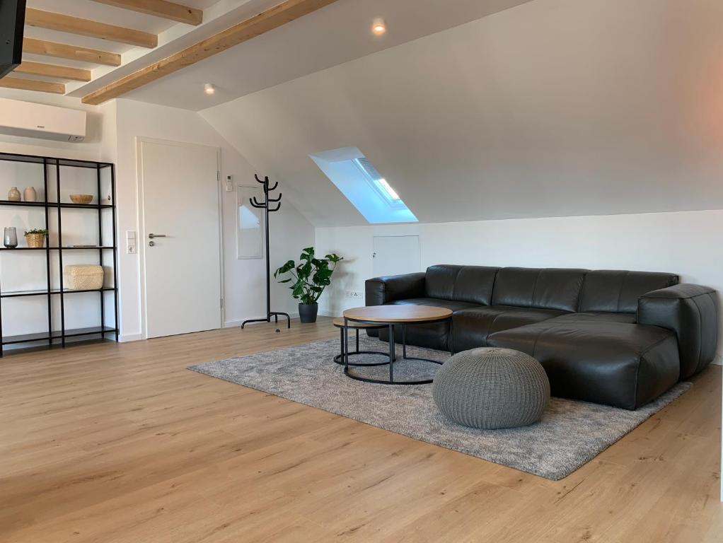 a living room with a black leather couch and a table at Klimatisierte Loftwohnung in Filderstadt