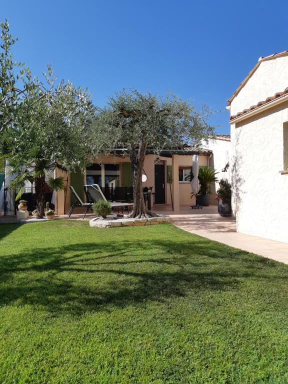 a yard with a tree and a house at Maison de vacances à Pégomas avec piscine - 3 chambres - 5 personnes - Jardin et parking privatif in Pégomas