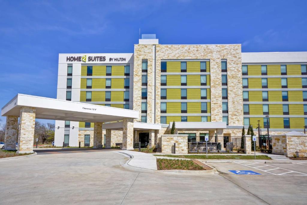 un hotel con un edificio blanco y amarillo en Home2 Suites By Hilton Plano Richardson, en Plano