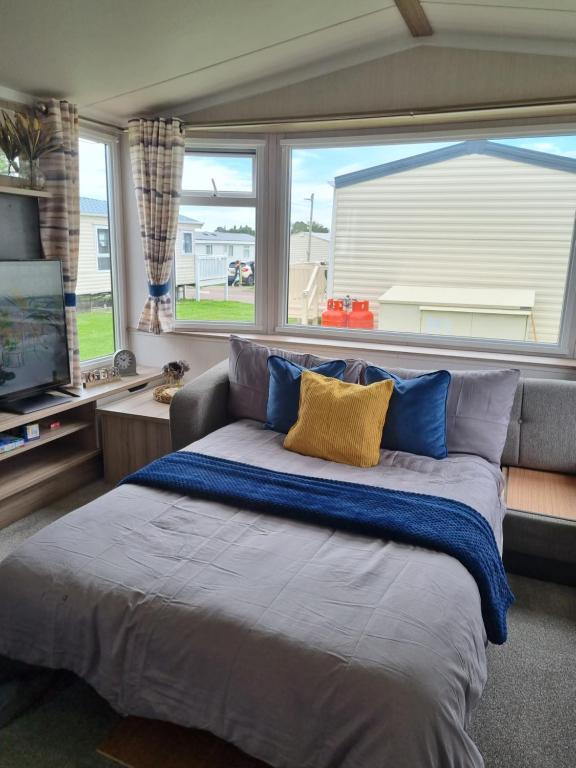a large bed in a room with a large window at Modern Family Caravan with WiFi at Valley Farm, Clacton-on-Sea in Great Clacton