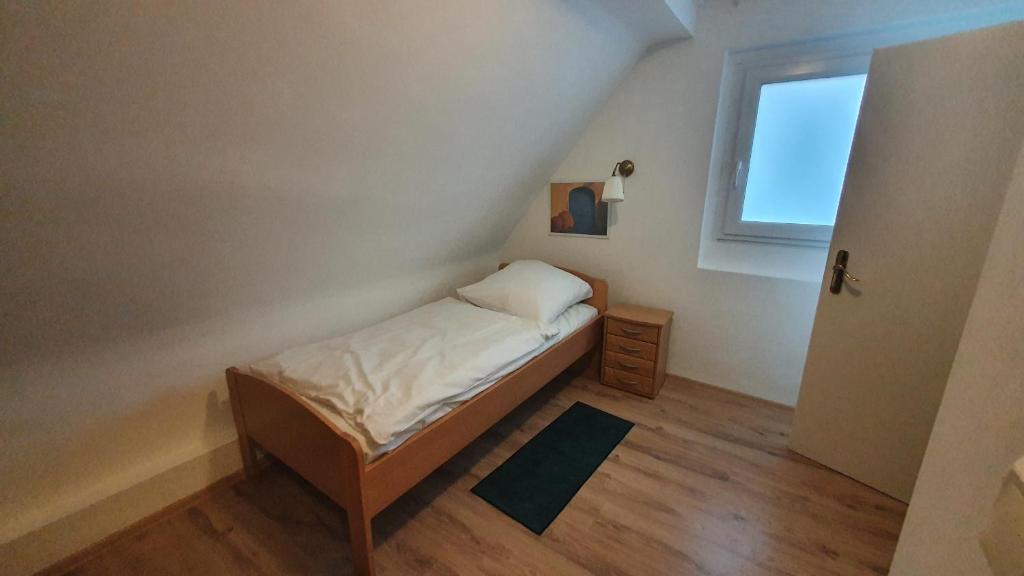 Habitación pequeña con cama y ventana en GreyGreen Residence I - Privates Bad, Gemeinschaftsküche und Aufenthaltsbereich, en Sehnde
