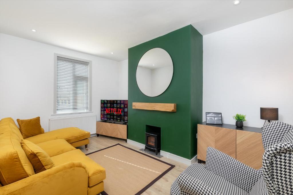 a living room with a yellow couch and a green wall at Charming Gateshead Retreat - Close to Newcastle - Angel of the North in Sheriff Hill