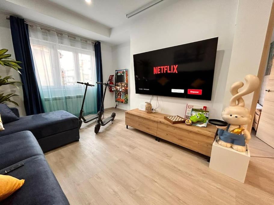 uma sala de estar com um sofá e uma televisão em LUJO: Proyector, Maquina Arcade, Wifi y Patinetes em Oviedo