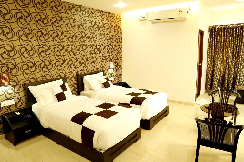 Cette chambre d'hôtel comprend deux lits, une table et des chaises. dans l'établissement Rydges Inn, à Kottakkal