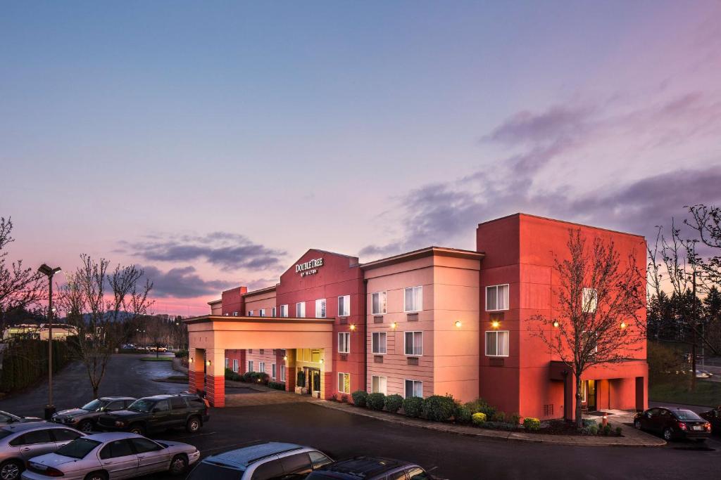 un gran edificio rojo con coches estacionados en un estacionamiento en DoubleTree by Hilton Portland - Beaverton, en Beaverton
