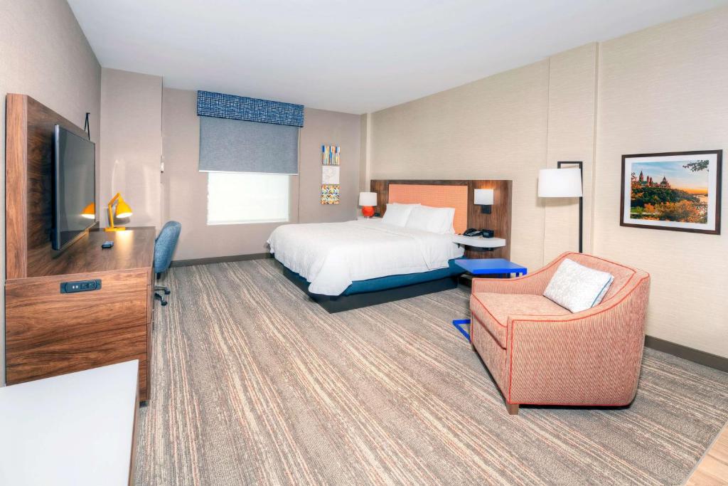 a hotel room with a bed and a chair at Hampton by Hilton Ottawa in Ottawa