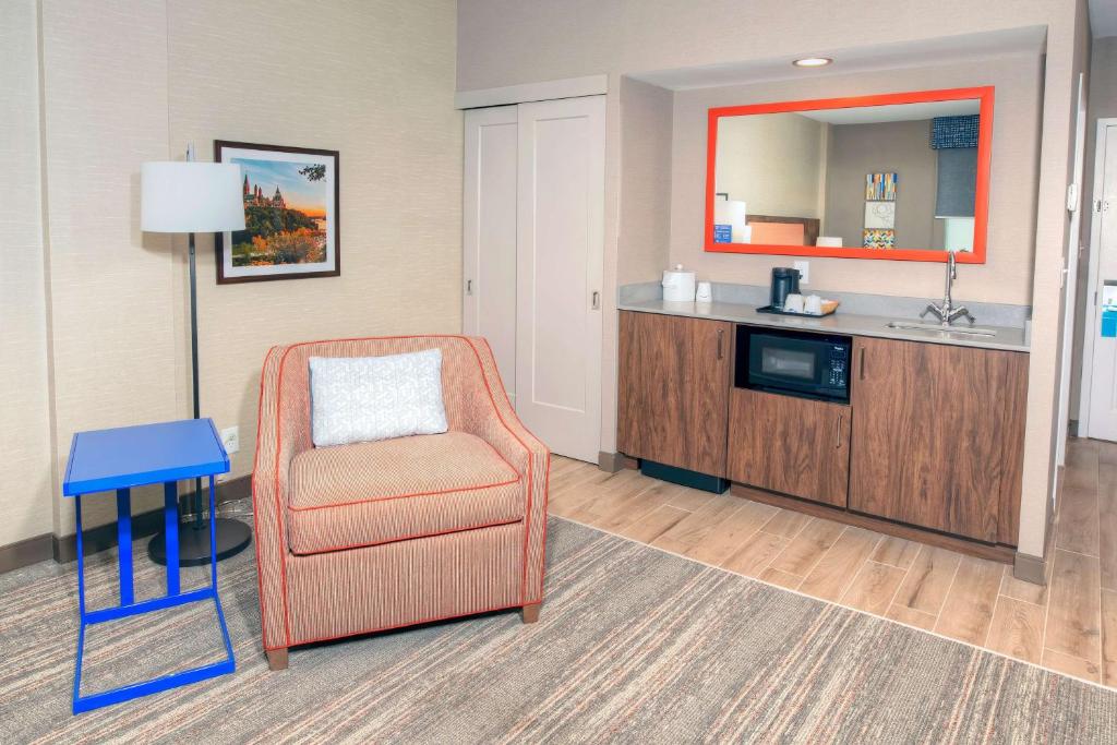 a hotel room with a chair and a sink at Hampton by Hilton Ottawa in Ottawa