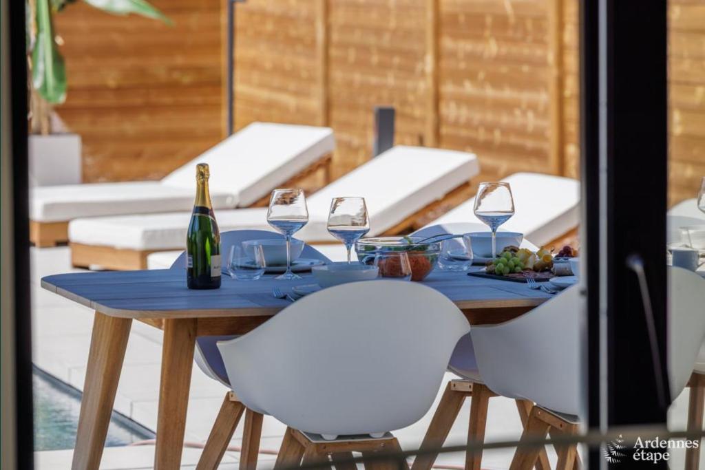 una mesa con 2 sillas blancas y una botella de vino en La Muse en Chiny