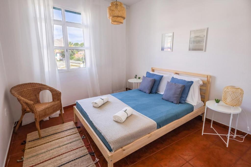 a bedroom with a bed and a chair and a window at SandyBeachApartment in Porto Santo