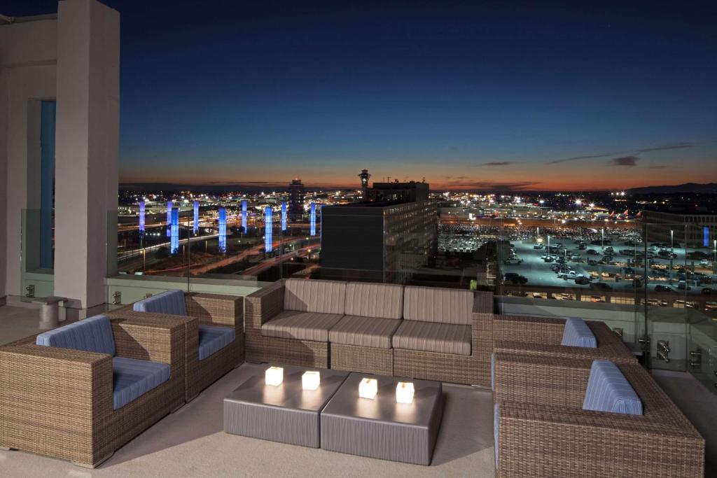 a rooftop patio with a view of a city at night at H Hotel Los Angeles, Curio Collection By Hilton in Los Angeles