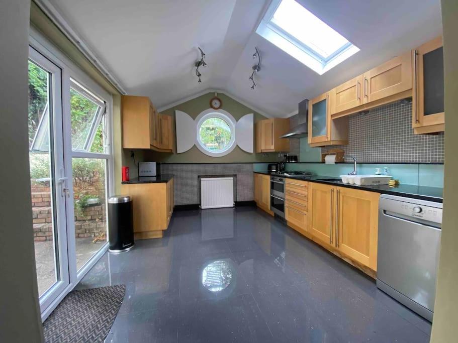 uma grande cozinha com armários de madeira e uma janela em Elegant flat in a fantastic area em Londres