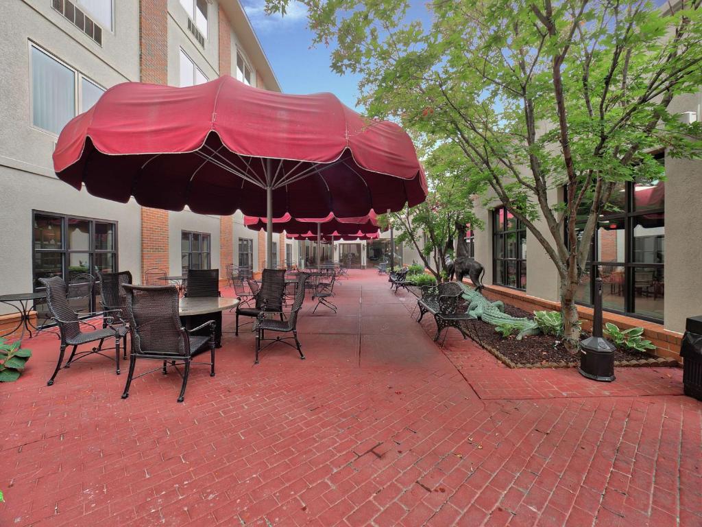 un patio con una mesa y sillas con una sombrilla roja en DoubleTree by Hilton Bloomington, en Bloomington