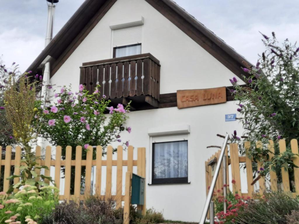 ein weißes Haus mit einem Holzzaun und Blumen in der Unterkunft Casa Luna in Donnerskirchen