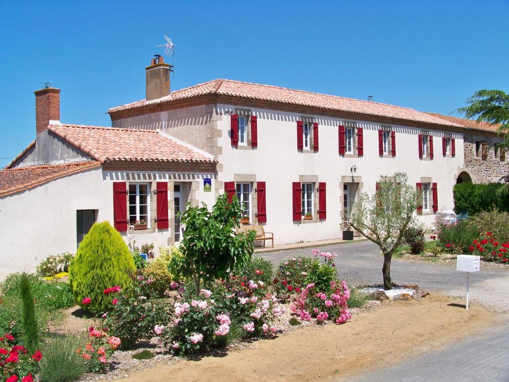 a large white building with red shutters and flowers at La Genoise in Tillières