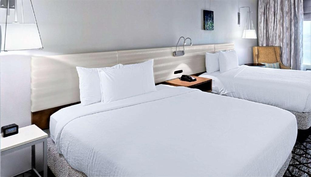 a hotel room with two beds with white sheets at Hilton Garden Inn Houston Cypress Station in Westfield