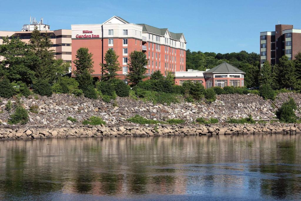 a building on the shore of a body of water at Hilton Garden Inn Auburn Riverwatch in Auburn