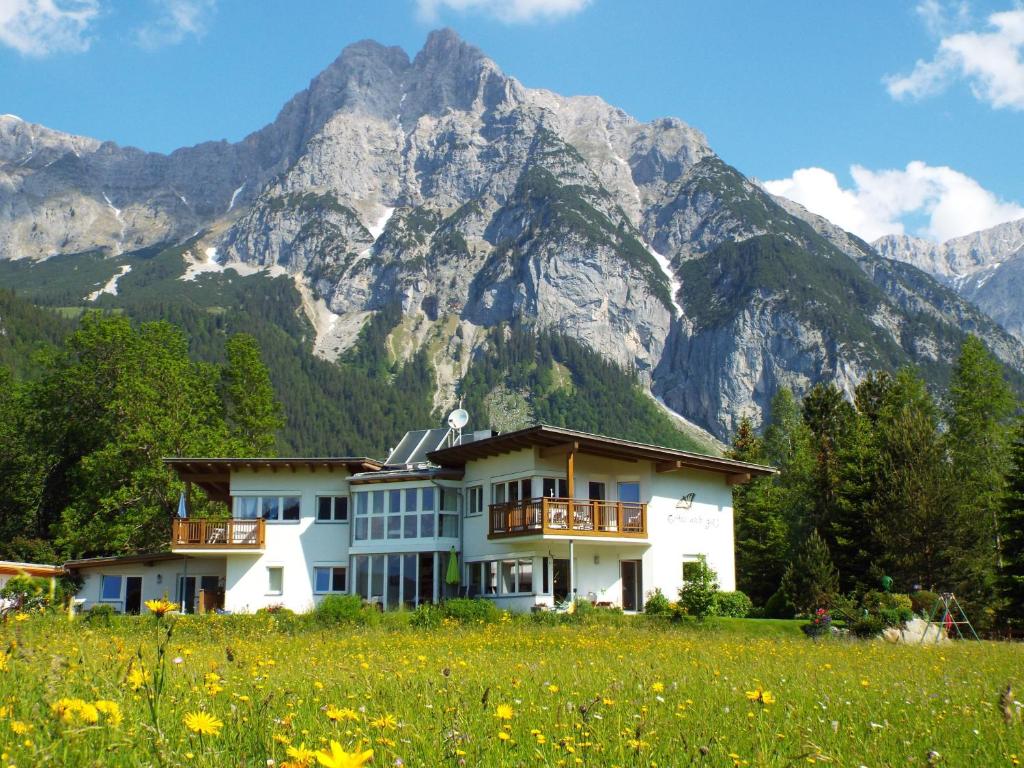 a house in a field with mountains in the background at Appartements Erhol dich gut in Leutasch