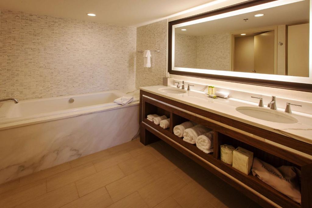a bathroom with a sink and a tub and a mirror at DoubleTree by Hilton Pittsburgh-Green Tree in Pittsburgh