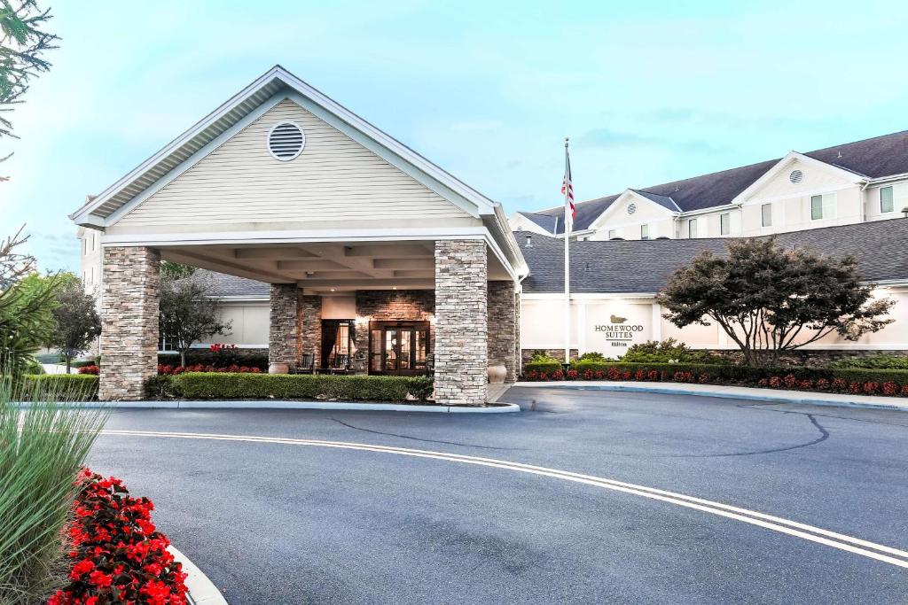 a house with a driveway in front of a building at Homewood Suites by Hilton Long Island-Melville in Plainview