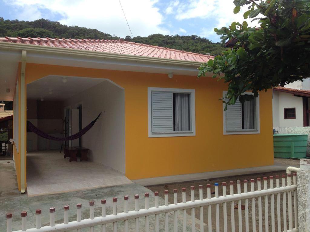 Aconchego Lagoinha Casa Frente في فلوريانوبوليس: منزل أصفر صغير مع سياج أبيض