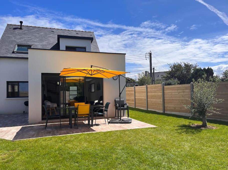 - une terrasse avec une table et un parasol dans la cour dans l'établissement Maison de vacances à 200 m de l'Aber Benoît, à Landéda