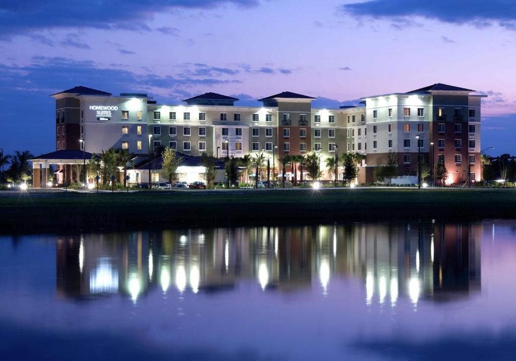 a large building with its reflection in the water at night at Homewood Suites Port Saint Lucie-Tradition in Port Saint Lucie